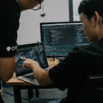 two men working on laptop programming